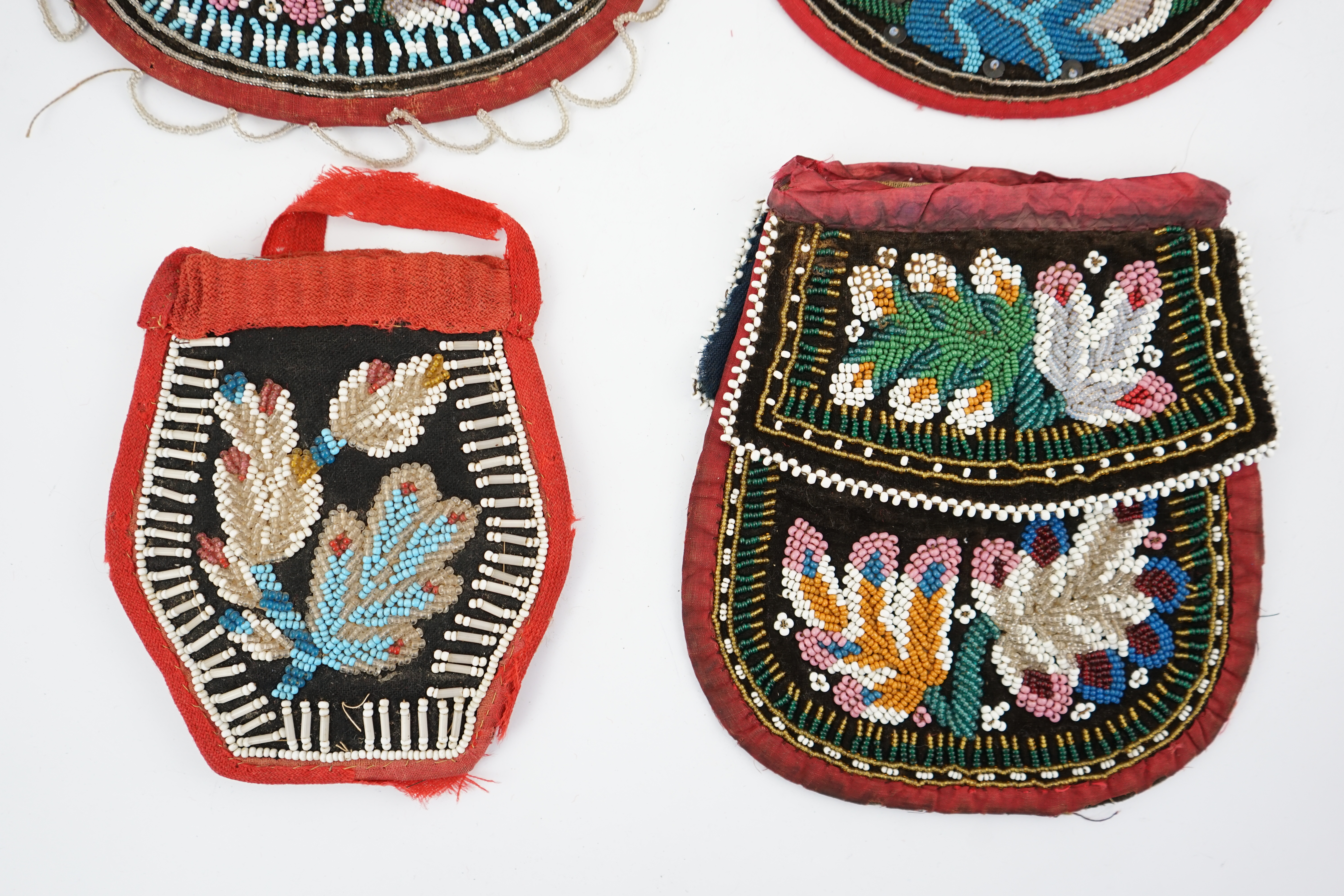 Three 19th century Iroquois Native American beaded bags and a smaller pouch, the bags have beaded flaps, the pouch is shaped with mostly white and turquoise beading having a red fabric edging, all four have very differen